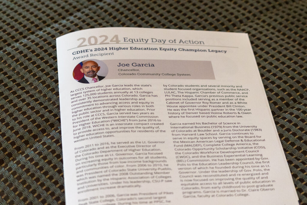 Close-up of a printed program page titled '2024 Equity Day of Action,' featuring a profile of Joe Garcia, Chancellor of the Colorado Community College System. The page highlights his achievements and leadership in higher education equity.